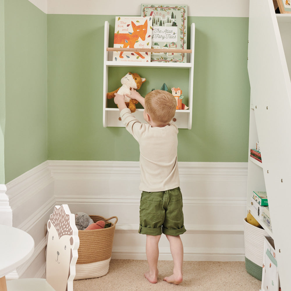 Child putting toy on wall shelf