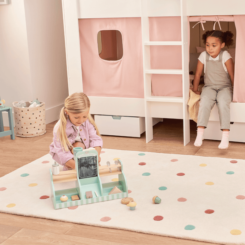 Two children playing in a room with a white bunk bed and colorful rug.