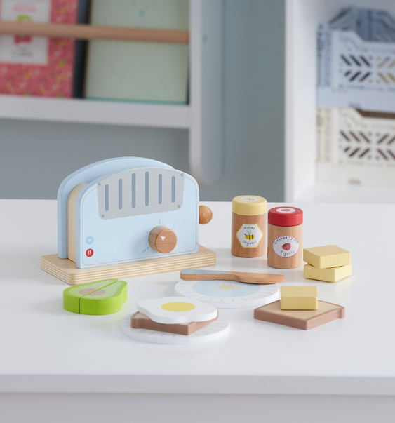 Wooden toy kitchen set with toaster, avocado, toast, and eggs on a beige background