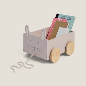 Children's toy cart with rabbit design holding books on a light beige background