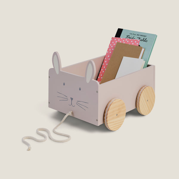 Children's toy cart with rabbit design holding books on a light beige background