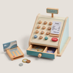Wooden toy cash register with card reader and coins on a light background