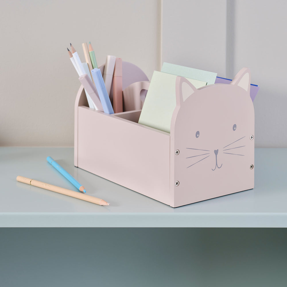 Pink cat-shaped pencil holder with stationery on a light gray surface