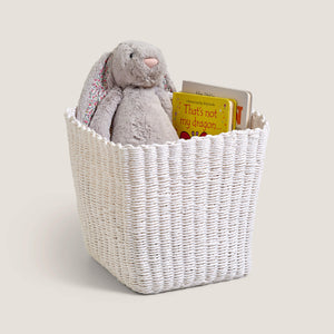 White woven basket with a plush toy and books on a light background