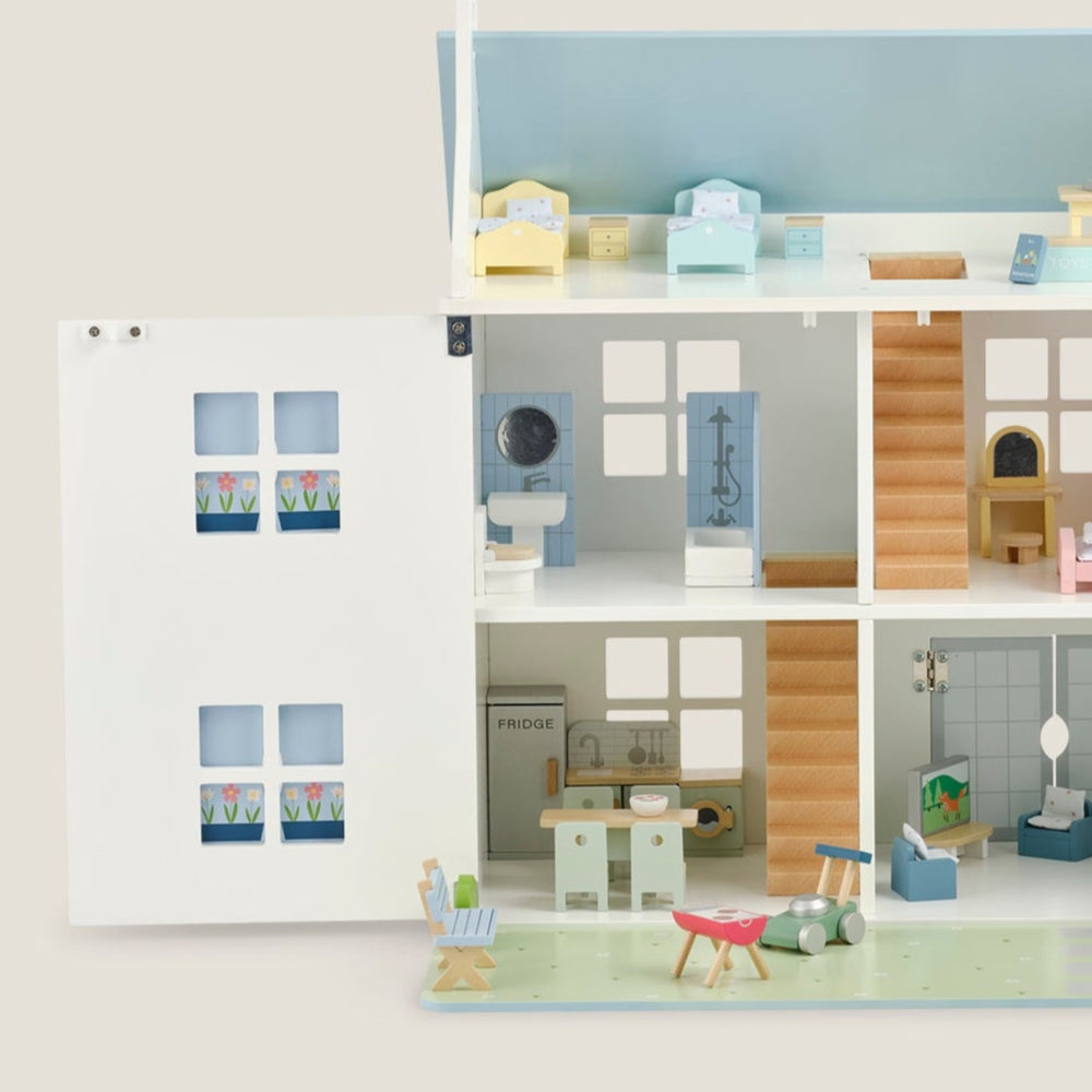 Set of toy kitchen furniture including a refrigerator, dining table with chairs, and cabinets on a light beige background.