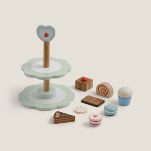Wooden toy cake stand with various miniature food items on a light background